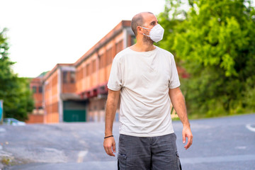 A young man with a mask outside his orange factory walking. Health emergency, pandemic Covid-19