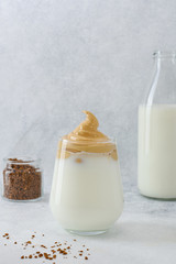 Dalgona coffee in glass with ingredients on light background with copy space. Whipped trend drink with coffee foam instant coffee and milk. Trendy drink during self quarantine of COVID-19.
