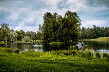 Summer landscape. The lake among the park. People are relaxing on boats.