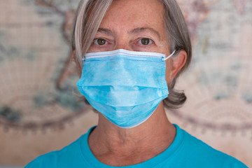 Portrait of senior woman wearing blue protective mask against coronavirus contagion, white background. Close up on face