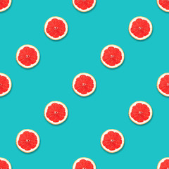 Pattern of fresh grapefruit slices on a turquoise background. Seamless texture. Top view, flat lay.