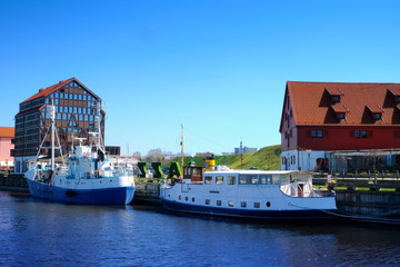Jetty for boats and yachts in Klaipeda, Lithuania, on sunny day. Beautiful view of vessels and fachwerk and red-brick houses