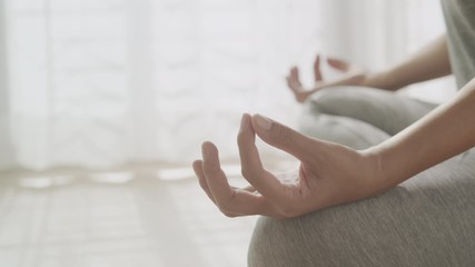 Hand of women in lotus pose while sitting at the floor and curtain white in the morning sunlight at home. Dolly shot, Concept of relaxation and meditation