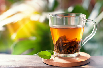 Black tea in glass cup on wooden table.