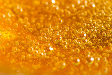 Detail of abstract orange bubble, can be used for background. Paste for sugaring close-up. Depilation and hair removal concept. Macro photography.