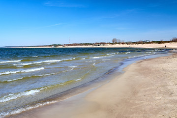 Seascape of Baltic sea and beaches in Klaipeda, Lithuania. Mild waves beat on cold pink sand on sunny spring day. Beautiful view.