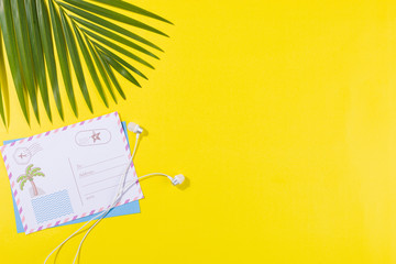 Beach accessories on a yellow background - palm leaves, travel postcards, headphones Summer is...