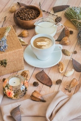 Still life details of home interior. A cup of coffee with milk and coffee beans on a wooden table. The concept of coziness and home atmosphere. Cozy autumn composition