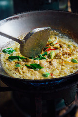 Cooking green curry with wok and spatula