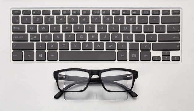 Top view of the keyboard of a laptop and glasses. The concept of damaged laptop vision