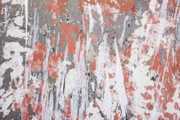 Old dirty urban wall with torn paper posters, peeling paint and damaged surface texture background.