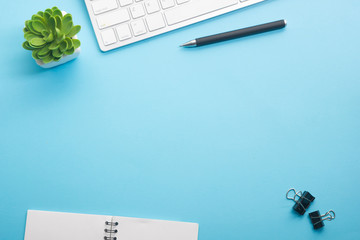 Blue desk office with laptop, smartphone and other work supplies with cup of coffee. Top view with...