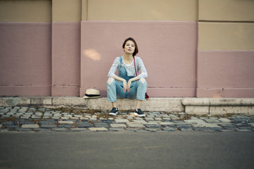 A girl is sitting in front of a pink background