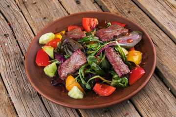 Veal salad with vegetables. Salad on a white plate.