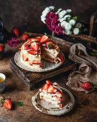 Obraz na płótnie Canvas cake with fresh strawberries and cream cheese on wooden board, rustic wooden background, seasonal dessert 