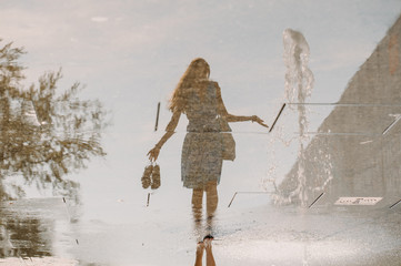 Reflection of a girl walking barefoot through a puddle