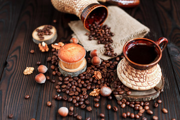 Fototapeta na wymiar hot fragrant coffee in a vintage clay cup and coffee beans with nuts on a dark wooden background