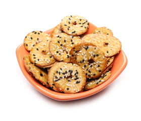 Baked pretzels with black and white sesame seeds, savory snacks in porcelain bowl isolated on white background