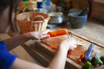 view of the hands of a young girl peeling a carrot in the kitchen