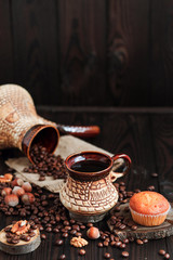 hot fragrant coffee in a vintage clay cup and coffee beans with nuts on a dark wooden background