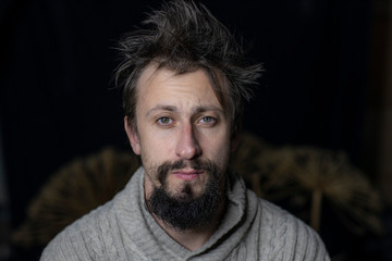Fototapeta premium a young man with a beard rumpled appearance in a sweater. The fight against alcoholism