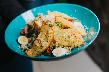 Vegetable and chicken salad named Caesar served with dried bread slices and Parmesan cheese