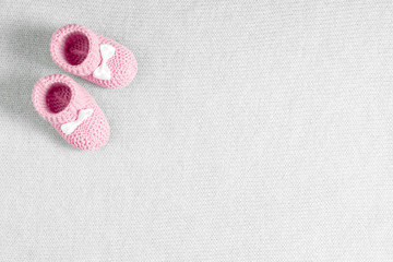 Pink toddler shoes on gray knitted blanket. Baby booties. Flat lay, top view, copy space