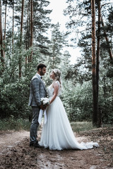 the bride and groom embrace in the forest on the wedding day. wedding ceremony. selective focus. film grain.
