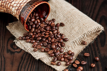 hot fragrant coffee in a vintage clay cup and coffee beans with nuts on a dark wooden background