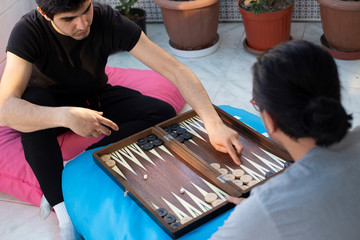 Two friends playing backgammon at home