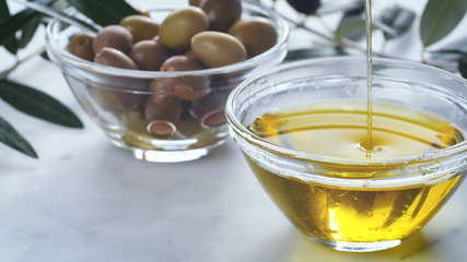 Extra Virgin oil falls on transparent bowl, white background. Genuine Italian ingredient, healthy food, natural product