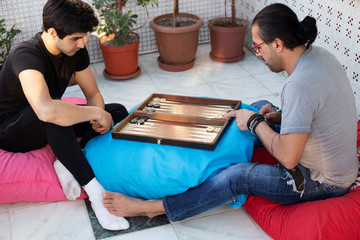 Two friends playing backgammon at home