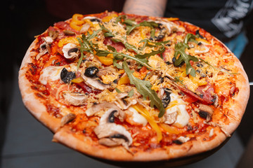 Tasty Italian pizza with cheese, pepperoni, arugula, cocktail tomatoes and  grilled bell pepper