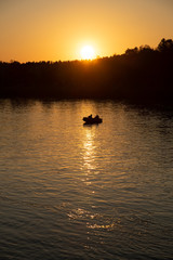 Naklejka na ściany i meble Sunset, boat, river and two men