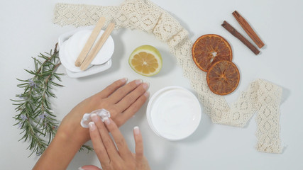  natural skin care, applying natural white cream on hands. Moisturizing treatment skin with natural ingredients. Cream, lemon, officinal herbs. white background