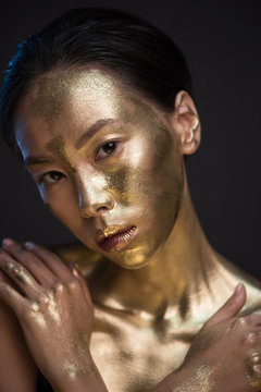 Portrait Of Young Asian Woman In Golden Paint