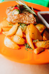 A piece of tasty grilled chicken steak covered with sauce on a plate served with grilled potatoes