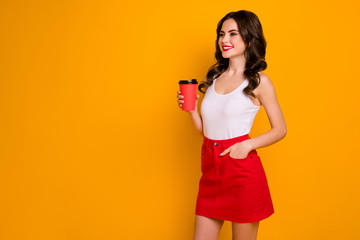 Photo of funny pretty lady hold paper cup takeaway hot coffee saturday look empty space meet friends wear casual white tank-top red skirt isolated vivid yellow color background