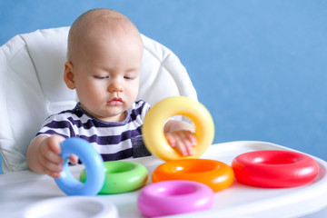 baby game. Little clever caucasian child playing colorful plastic toys pyramid sitting on highchair. games for early development. New born infant kids leisure.