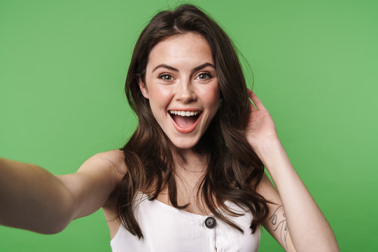 Image of excited attractive woman smiling and taking selfie photo