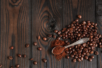 Roasted aromatic coffee beans on burlap, ground coffee in a spoon, on a dark wooden background