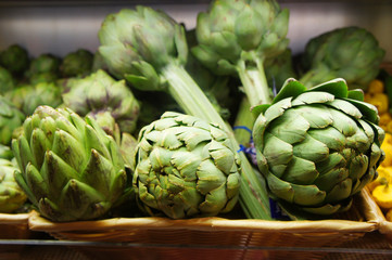 Obraz premium Close up of bunch of delicious green artichokes at the organic supermarket vegetables department shelve. Sustainable agriculture. Vegetarian and vegan food. 