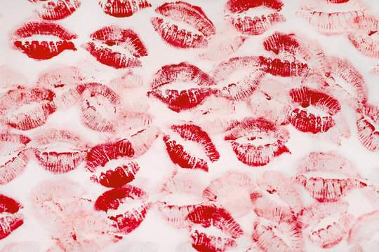 A lot of kissing marks made with the red lipstick on the white paper background - Image. Paper with lipstick kisses. Abstract passion love background.  Imprints of female lips. 