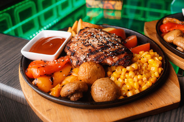 A piece of tasty grilled chicken steak covered with sauce on a plate served with grilled  tomatoes