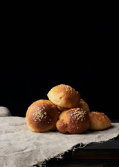 baked round bun with sesame seeds, black background, home baking