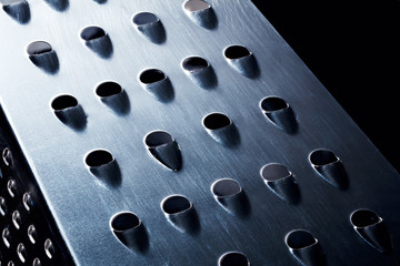 Metal chrome grater on black background.