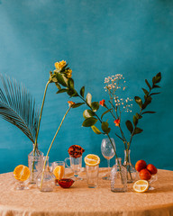 Citrus fruits and beautiful flowers in vases on a blue background