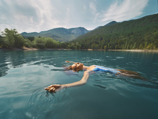 beautiful happy woman in blue swimwear relaxing, swimming and enjoying fresh colored water in mountain lake. beautiful scenery, people in nature and calmness concept