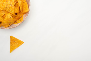 top view of crunchy corn nachos in bowl on white background