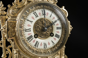 Fototapeta na wymiar dial of vintage bronze clock on black background, antique clock photo close up, old bronze clock in gilding, the second hour on the dial, two hours on antique clock 